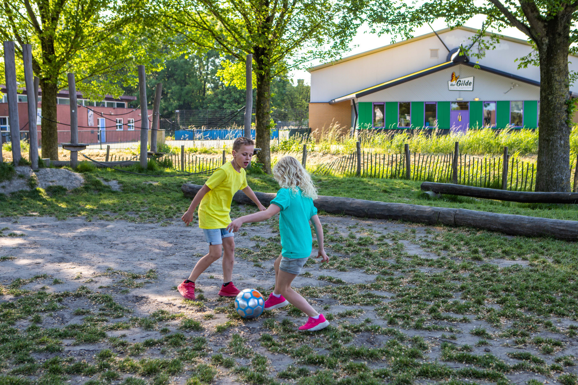 twee bso-kinderen voetballen buiten