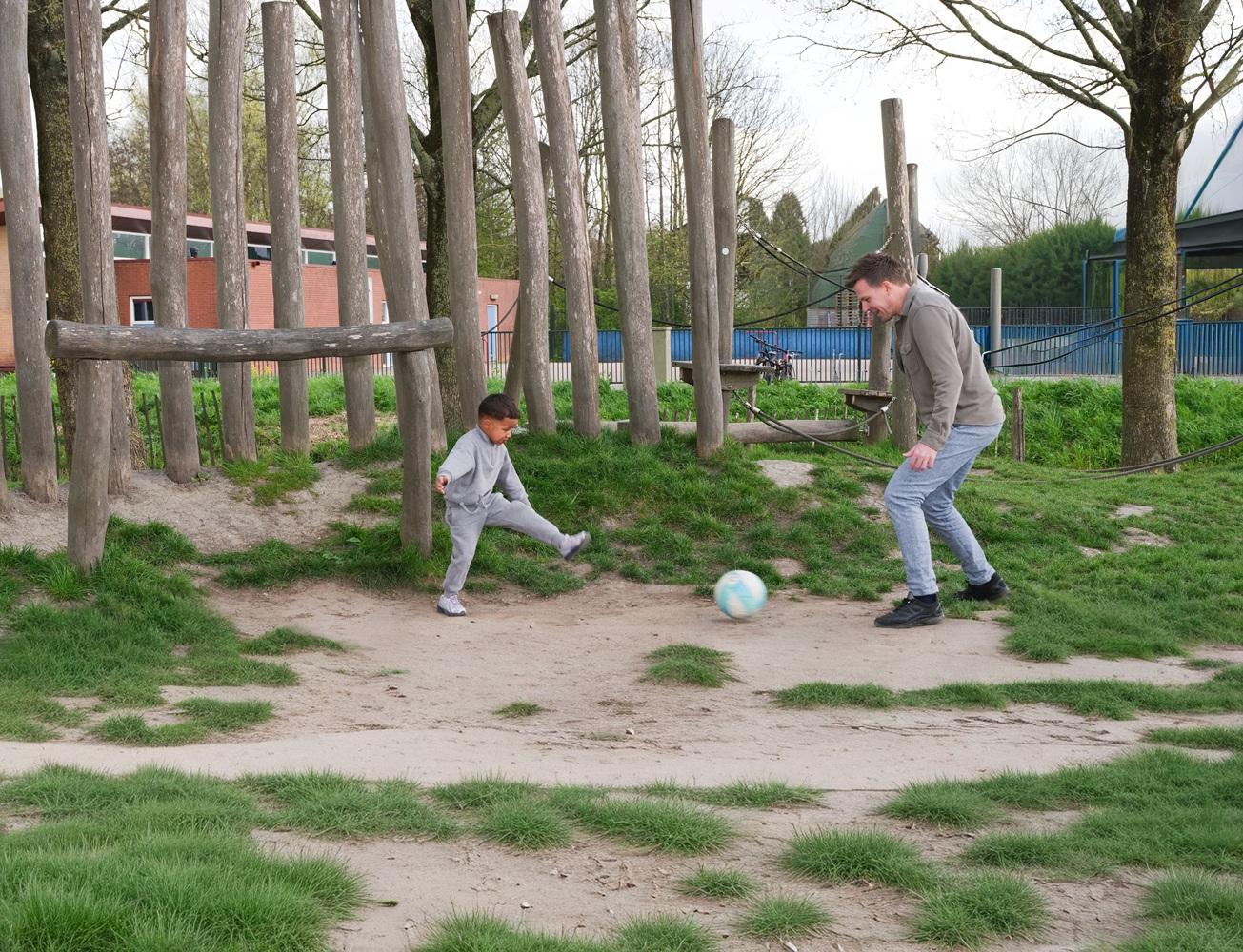 Pedagogisch professional en jongen spelen voetballen