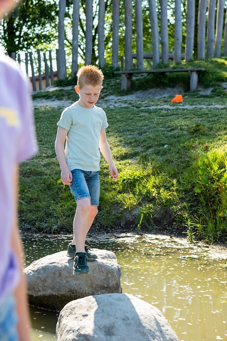 kind loopt over stenen op het water