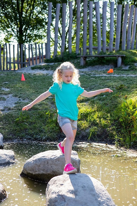 Meisje loopt op stenen over water