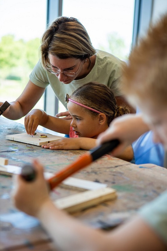 meisje is een knutselwerkje aan het timmeren met een pedagogische medewerker