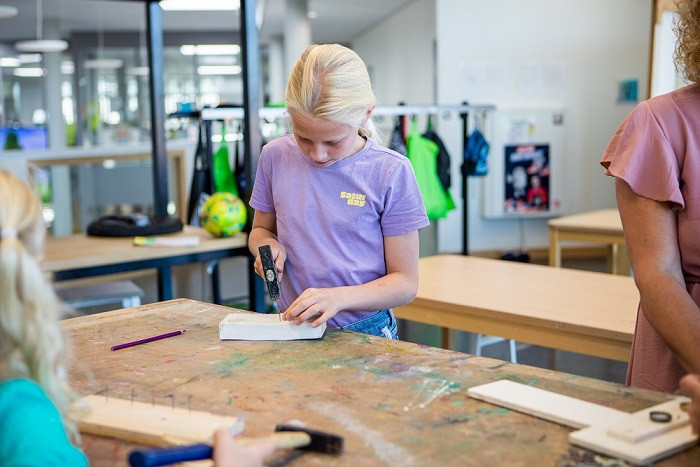meisje timmert spijker in plank