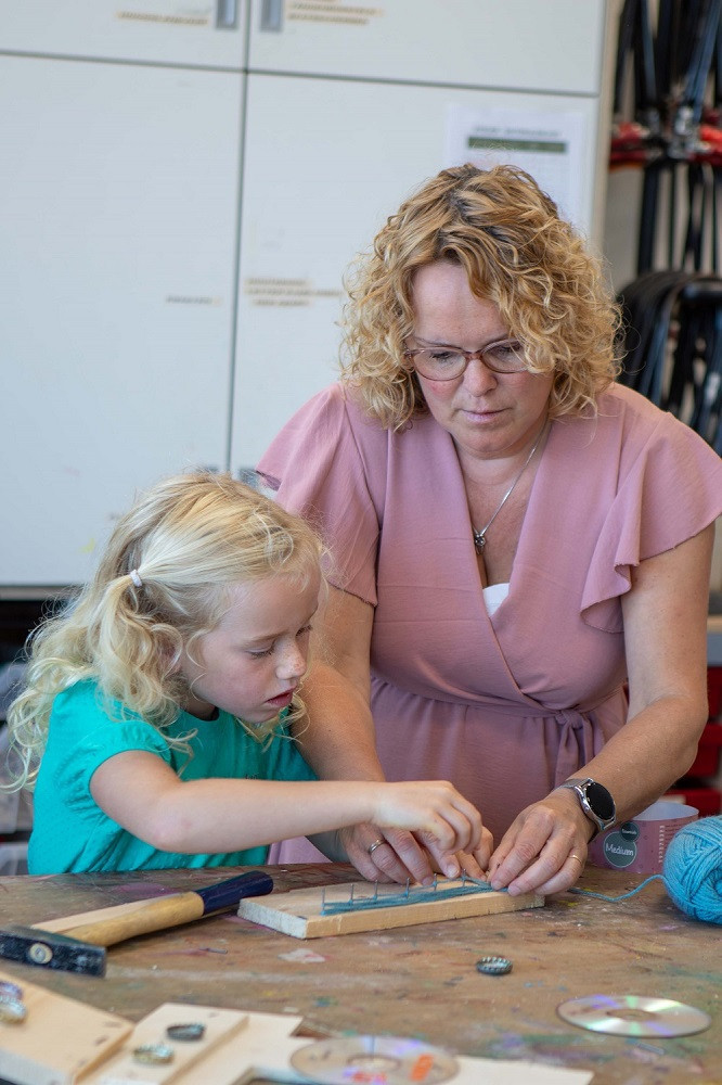 Meisje en pedagogisch medewerker knutselen samen