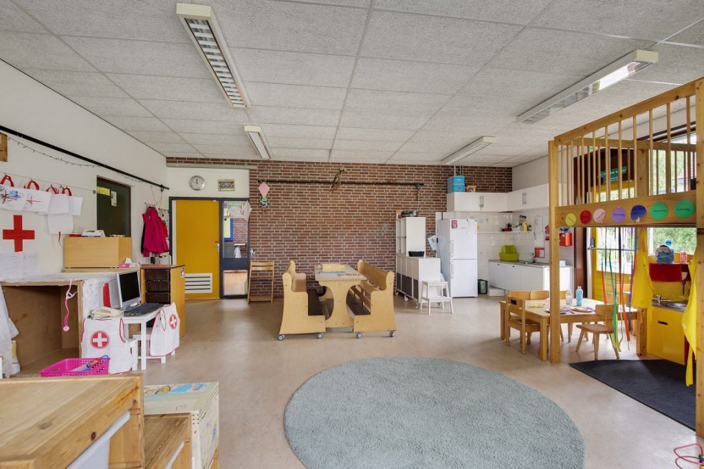 binnenruimte met verschillende speelhoeken, keuken en tafel