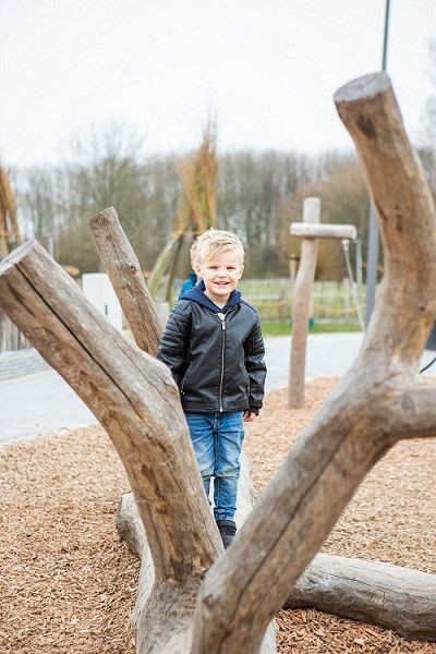 jongen staat op boomstronk