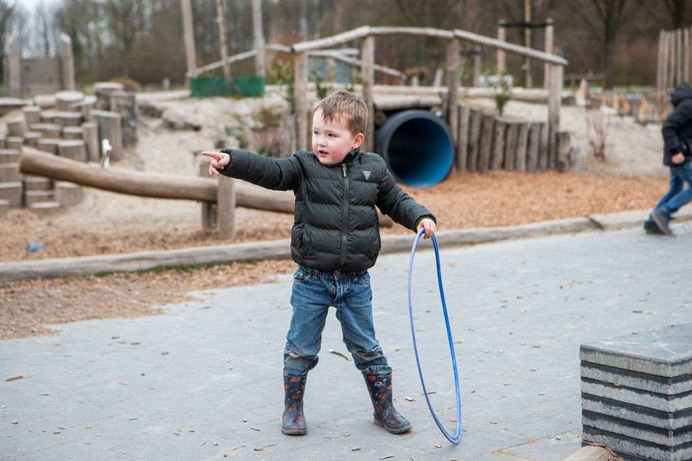 kind heeft hoepel in zijn hand en wijst