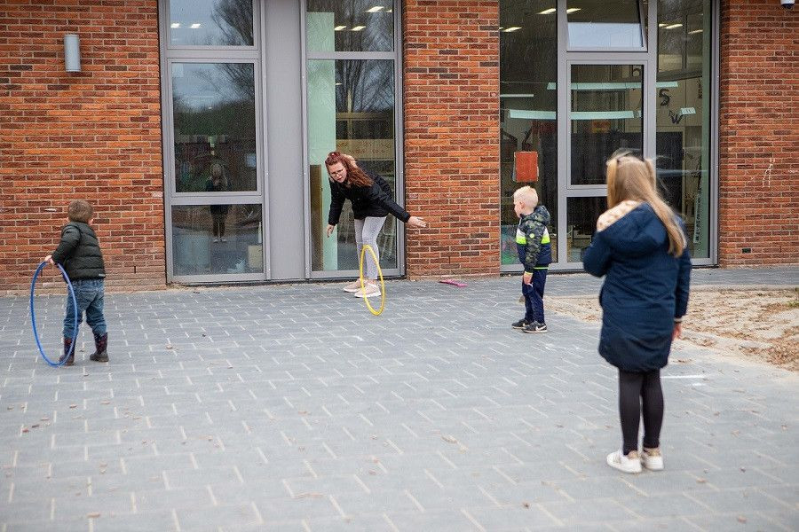 kinderen en pedagogisch professional spelen buiten met hoepels