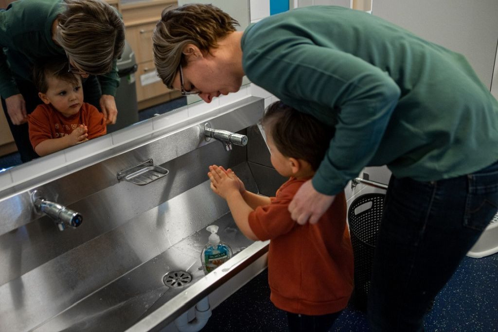 pedagogisch professional helpt kind met handenwassen