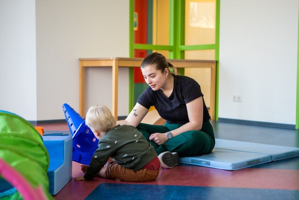 pedagogisch professional en kind met pion samen op de grond