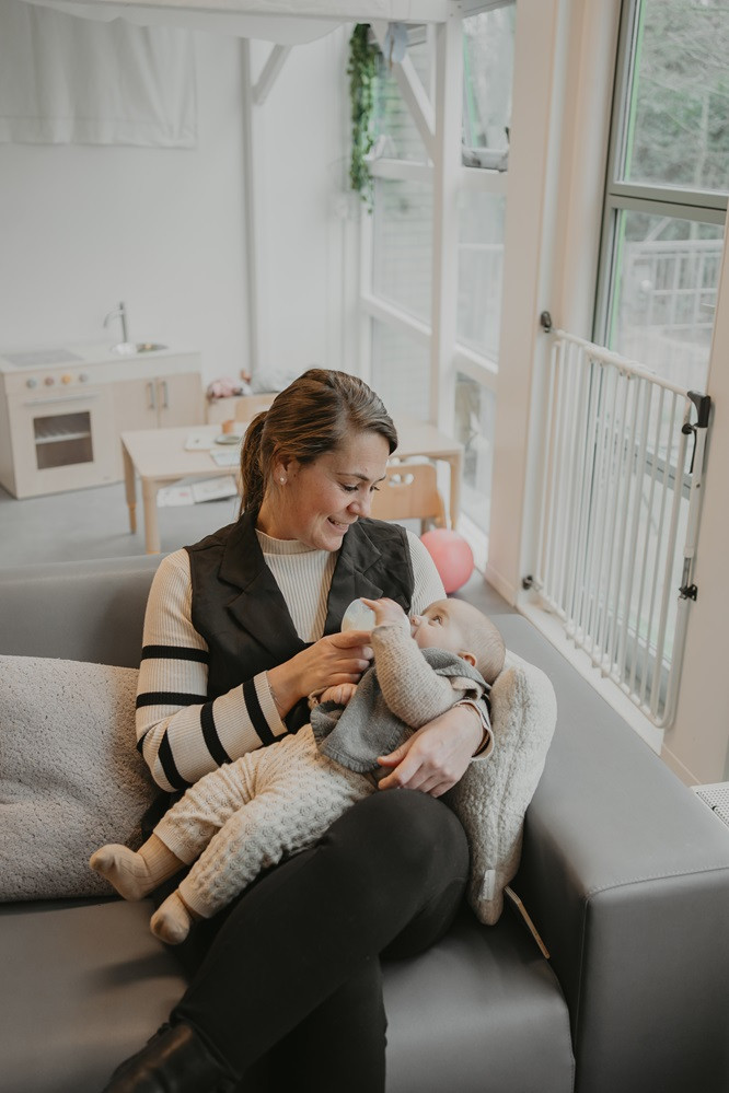 pedagogisch professional geeft fles aan baby