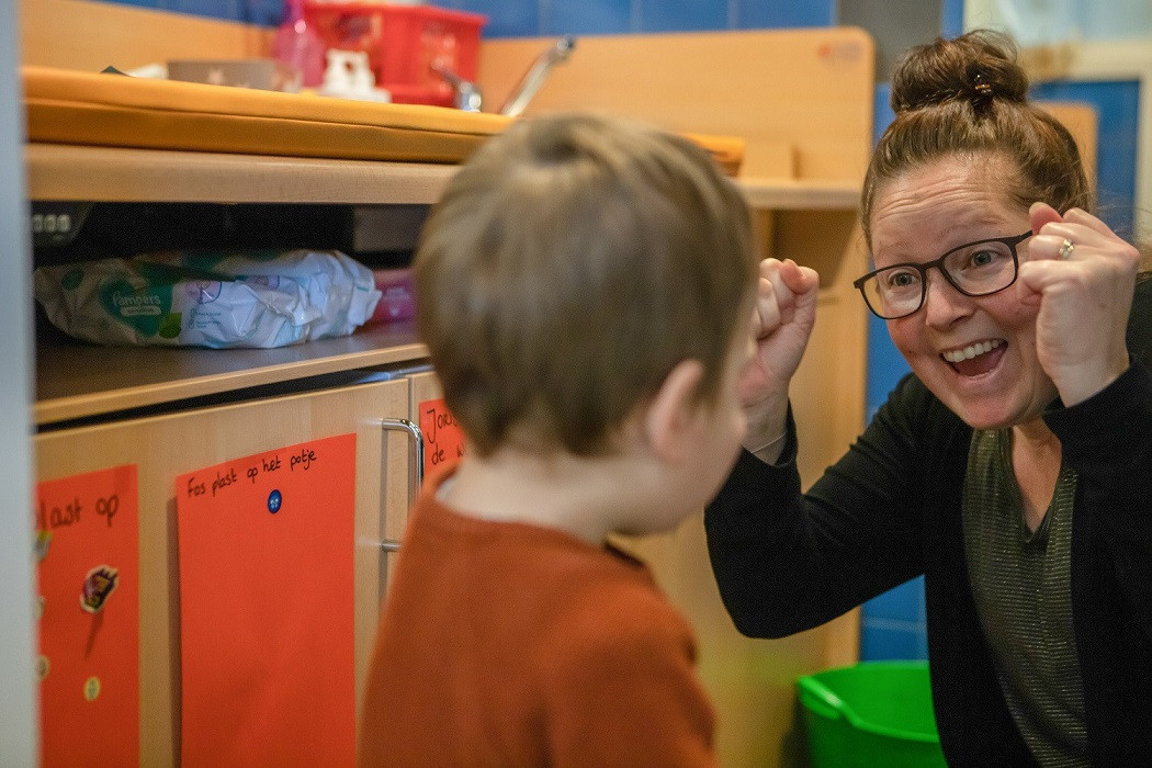 pedagogisch medewerker juicht naar kind