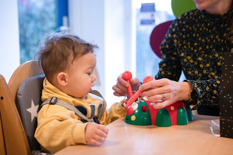 kind zit aan tafel en krijg speelgoed aangereikt