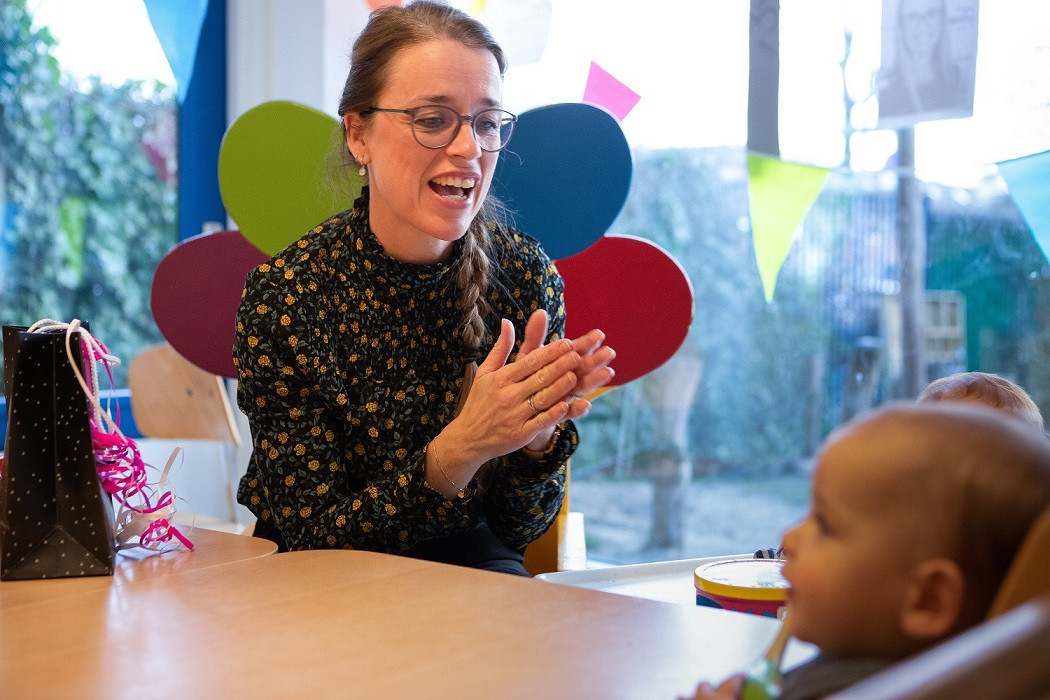 pedagogisch professional klapt in handen richting baby's