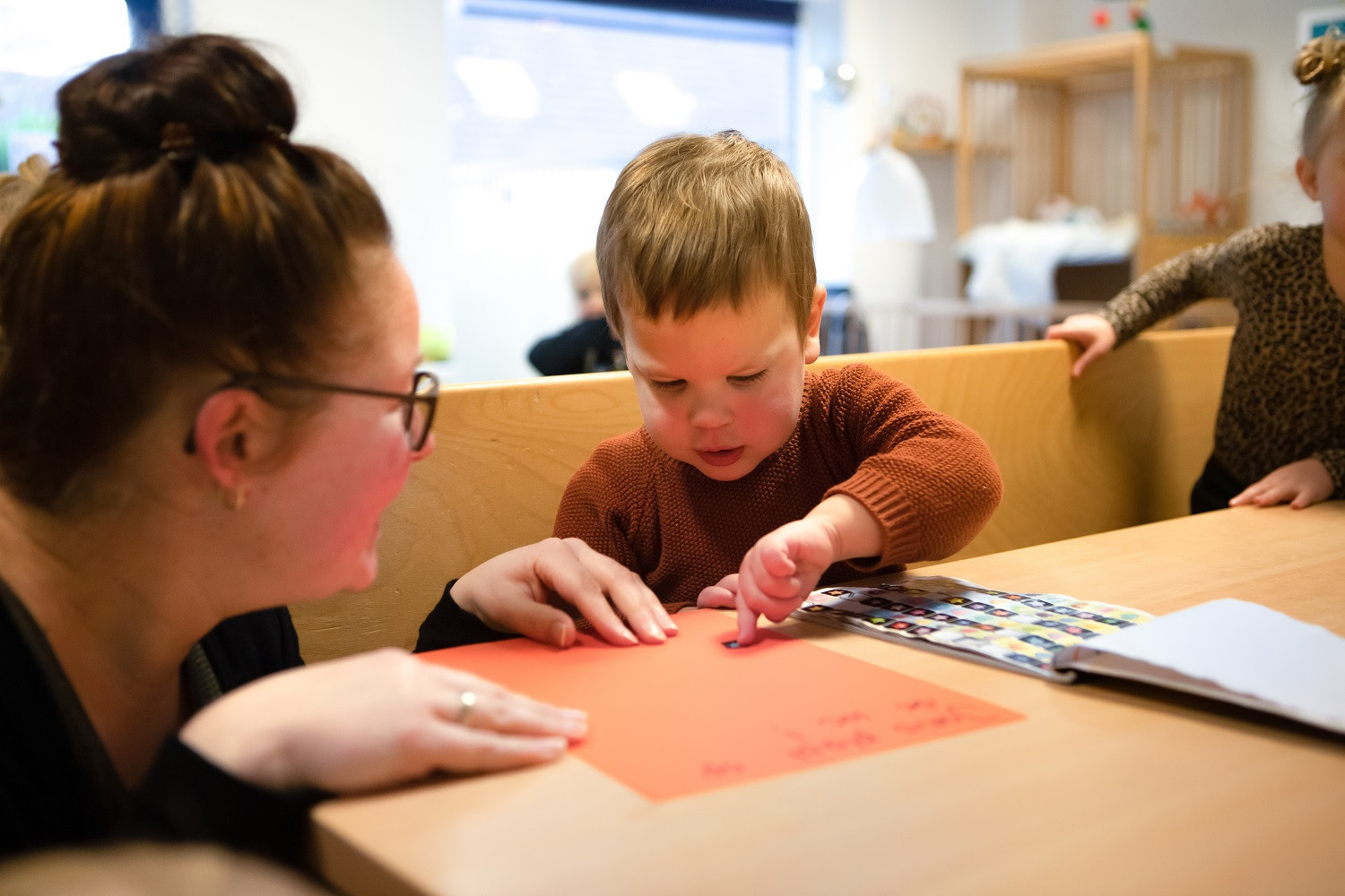 jongen plakt sticker op oranje vel papier