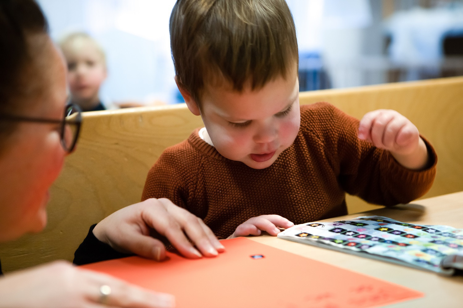 jongen is geconcentreerd sterren stickers aan het plakken op oranje vel papier