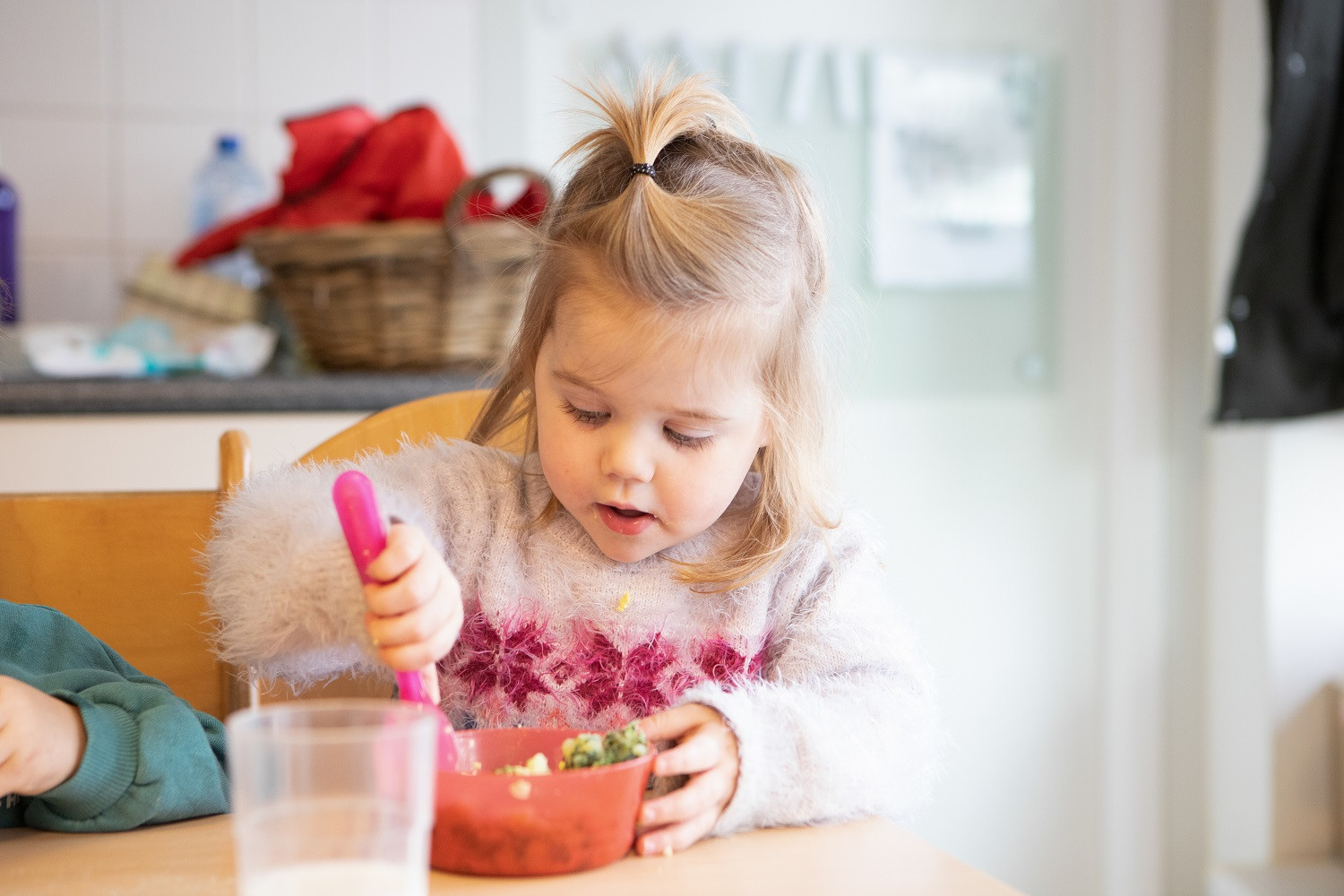 meisje eet boerenkool aan tafel