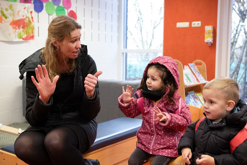 Pedagogisch medewerker en kinderen tellen met hun vingers