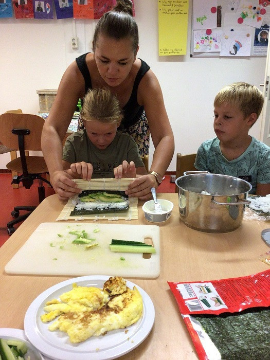 Pedagogisch professional en kinderen maken samen sushi