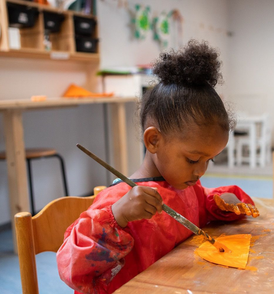meisje is een kartonnetje oranje aan het verven