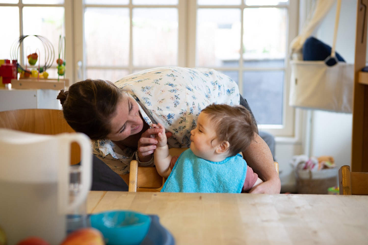 baby aan tafel met pedagogisch professional achter zich
