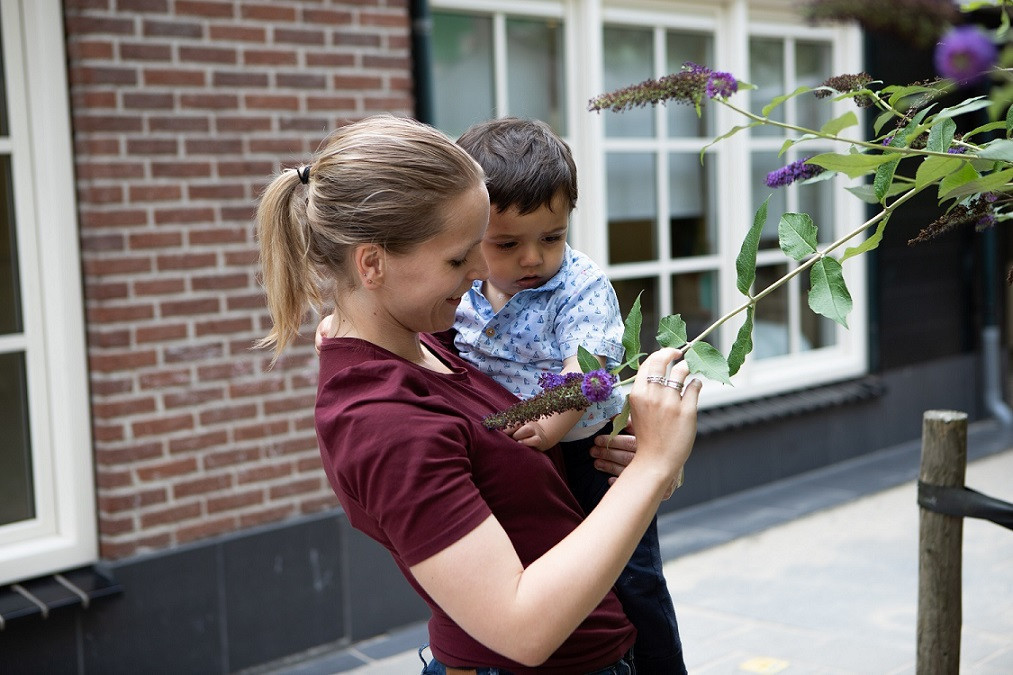 pedagogisch professional tilt jongen op om samen naar bloemen te kijken