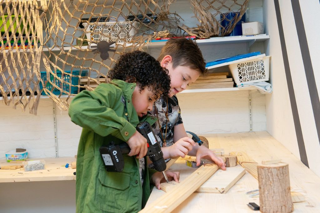 Twee jongens zijn een timmerwerk aan het maken van hout