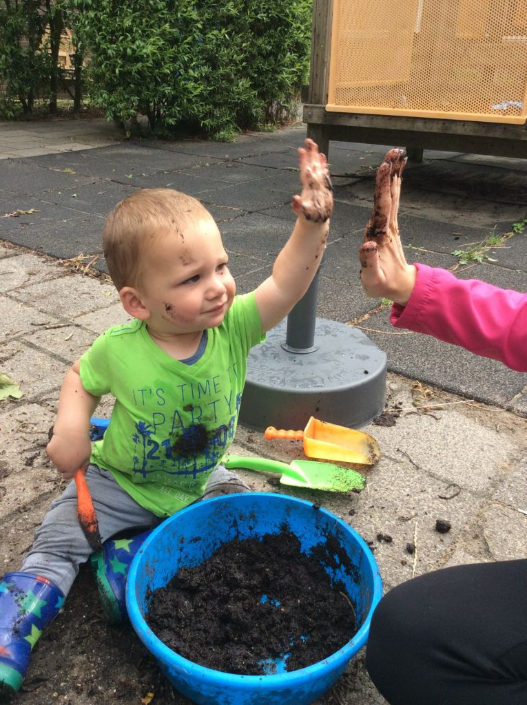 kind geeft high five met modderhanden