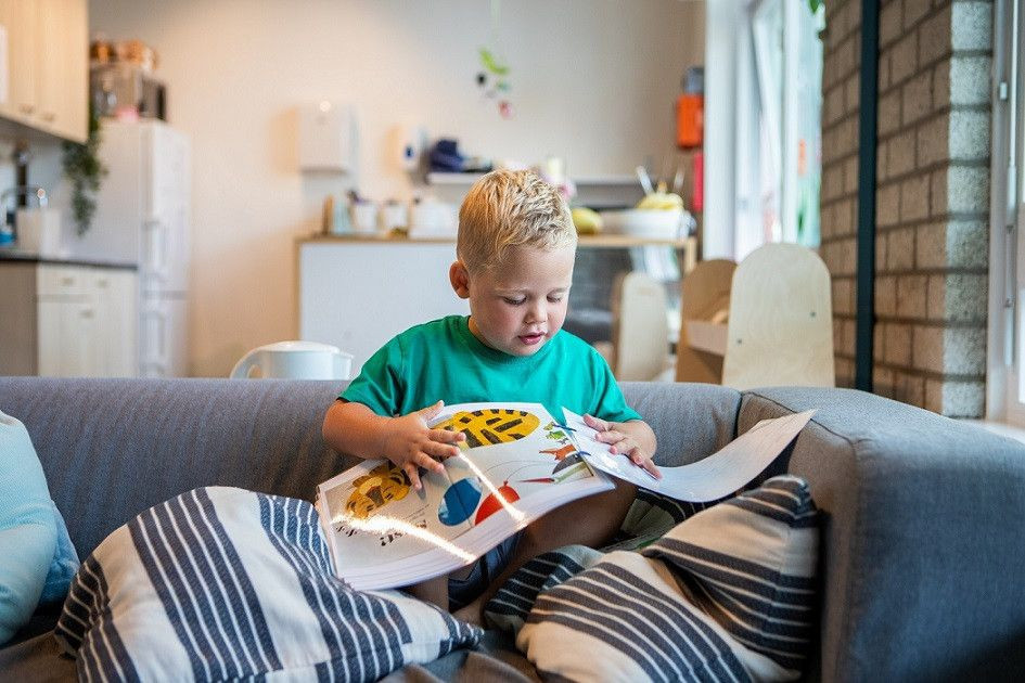 jongetje leest boek op bank