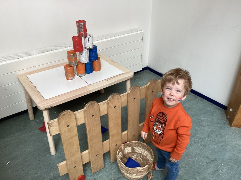 Kind staat bij blikken gooien in koningsdag style
