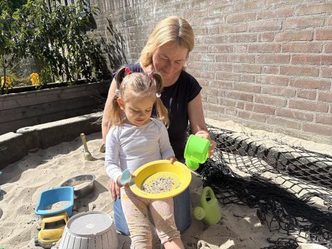 Pedagogisch professional Annemieke speelt met een peuter in de zandbak