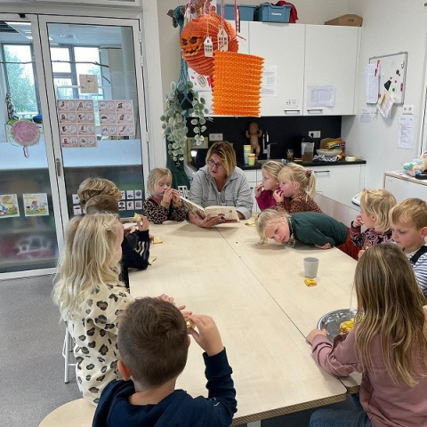 Pedagogisch professional leest voor aan groep kinderen