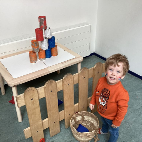 Kind staat bij blikken gooien in koningsdag style
